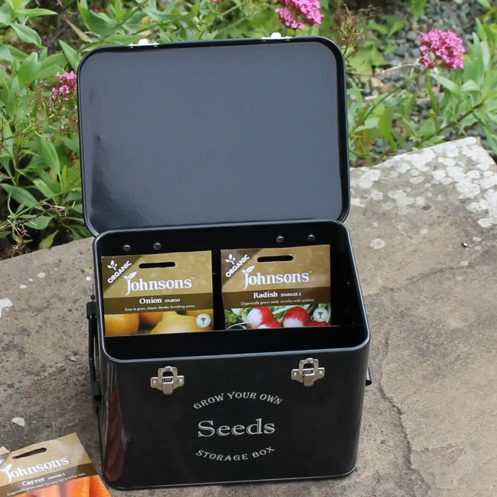 black seed tin with seed packets in. In garden